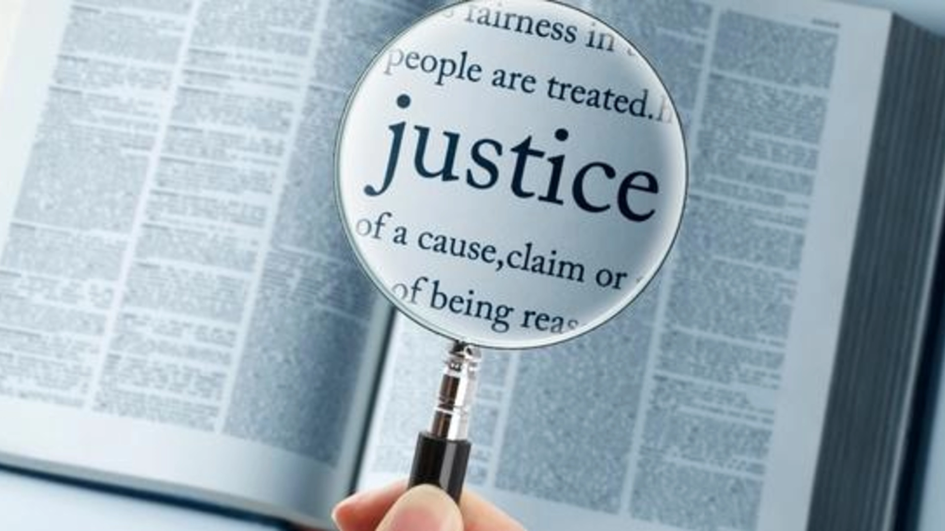 The word "justice" that is in a book and enlarged under a magnifying glass.