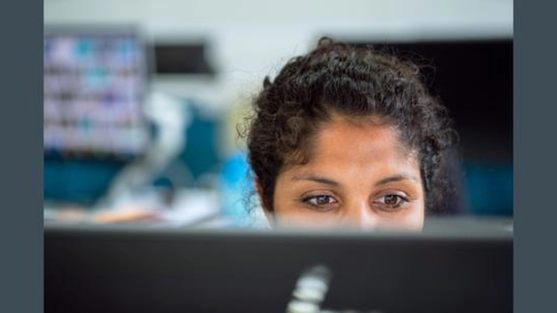 Looking at the upper part of a woman's face over the top of her computer screen.
