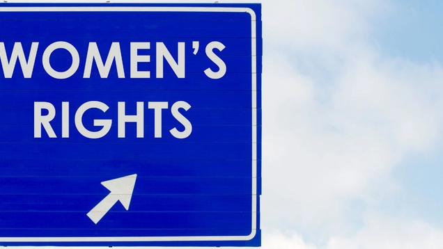 Stock photo of a dark blue freeway sign with the words, "Women's Right's" and an arrow in white. The sign is front of a blue sky with clouds.