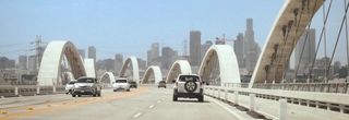 Wide photo of the new 6th Street bridge near downtown Los Angeles with a few cars on it.